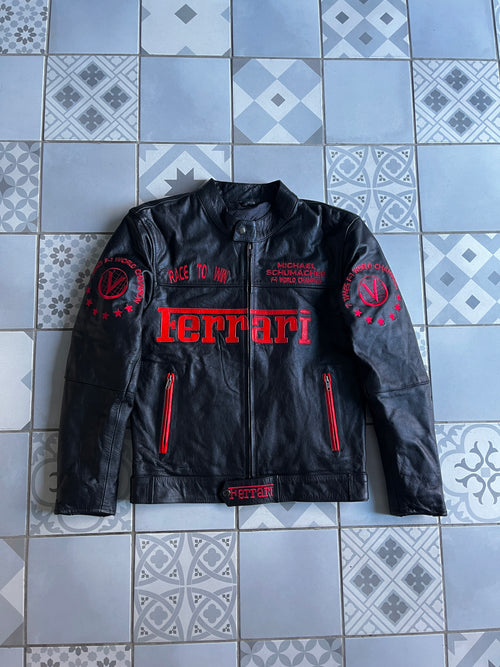 Vue de face du blouson cuir vintage Ferrari noir, avec broderies rouges Michael Schumacher, Race to Win et logo Ferrari sur la poitrine.