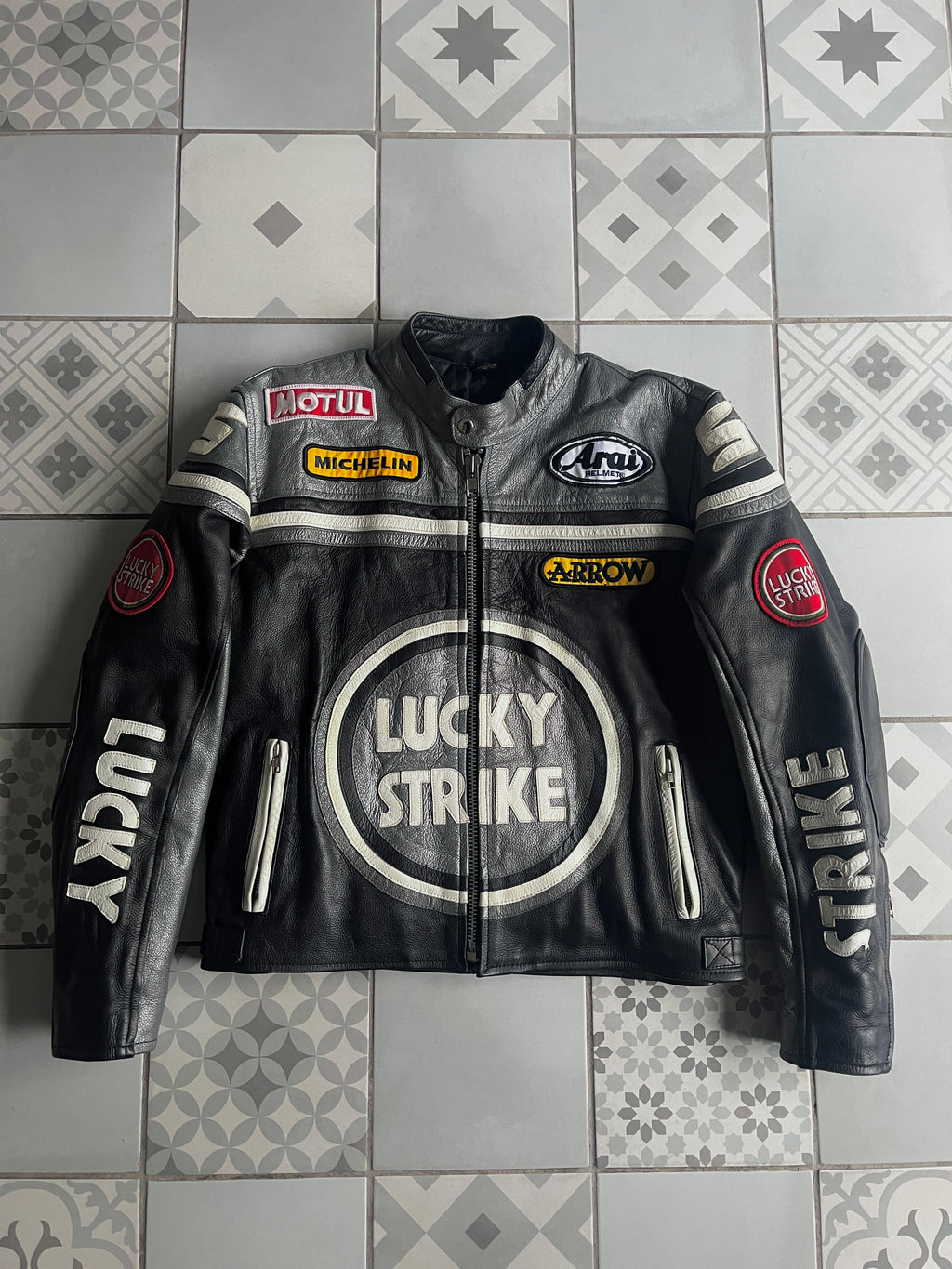 Vue de face du blouson moto vintage Lucky Strike édition Kevin Schwantz en cuir noir et argent, avec logos Michelin et Motul