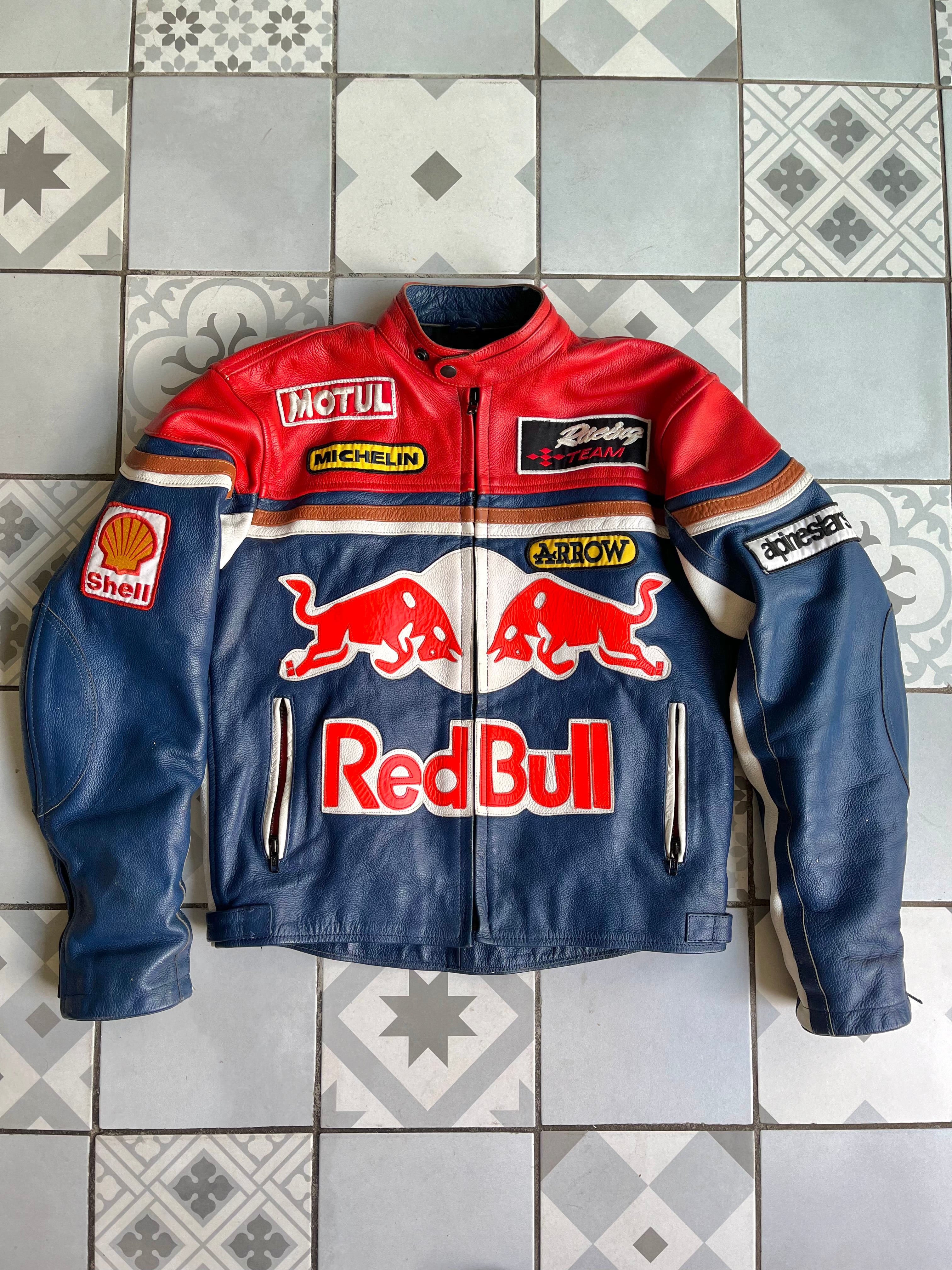 Vue de face complète du blouson cuir vintage Red Bull Racing bleu rouge blanc, avec logos sponsors Motul, Michelin et taureaux rouges.
