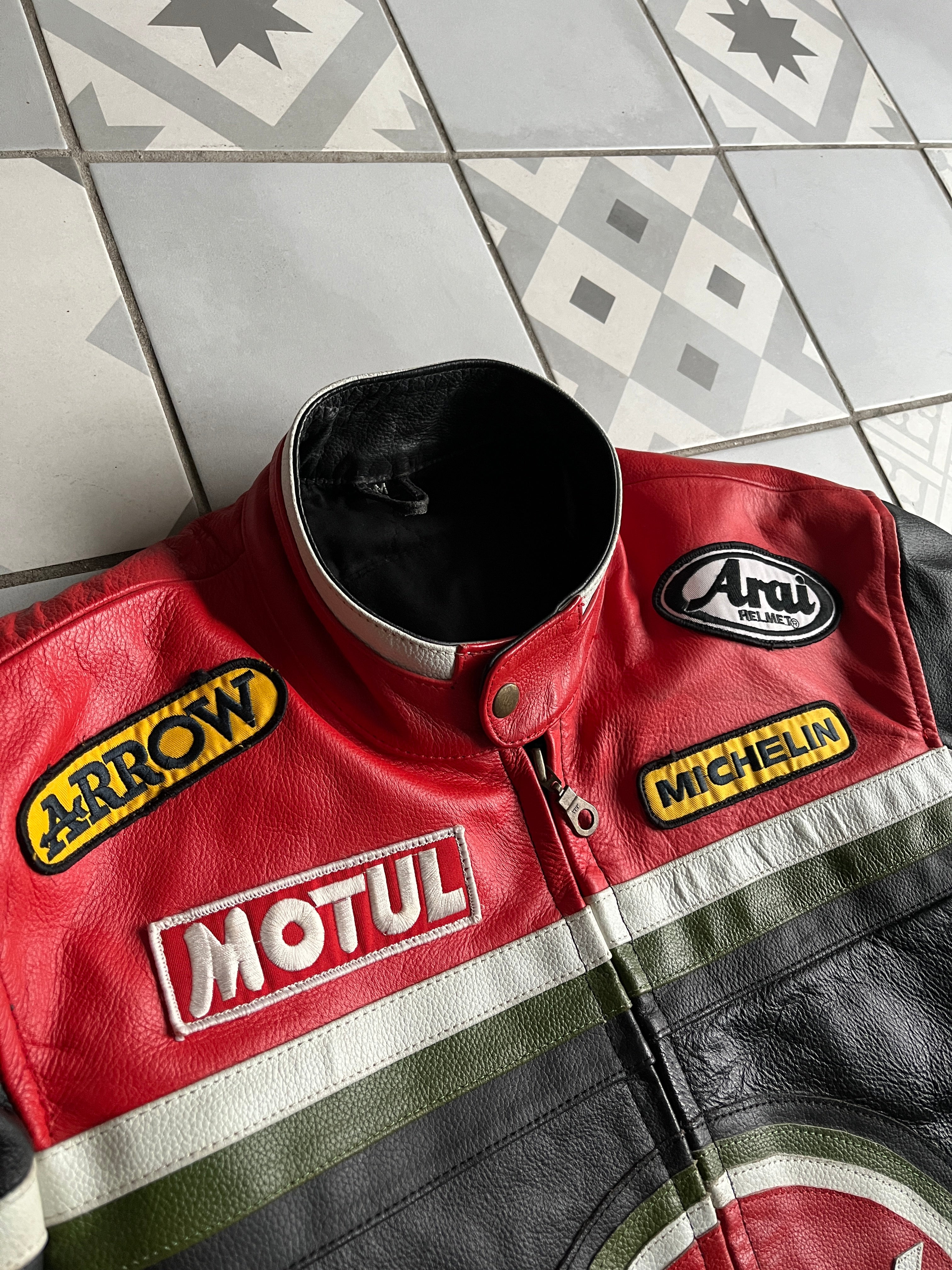 Détail du col motard à pression et des épaules rouges avec patchs Arai Helmet, Arrow et Motul sur veste racing