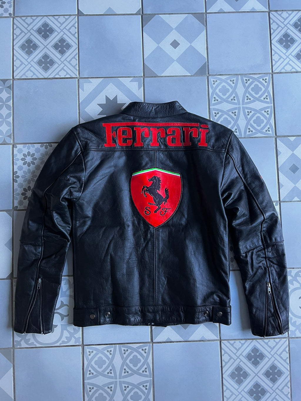 Vue arrière complète de la veste, affichant l'immense logo Scuderia Ferrari central et le texte Ferrari rouge sur les épaules.