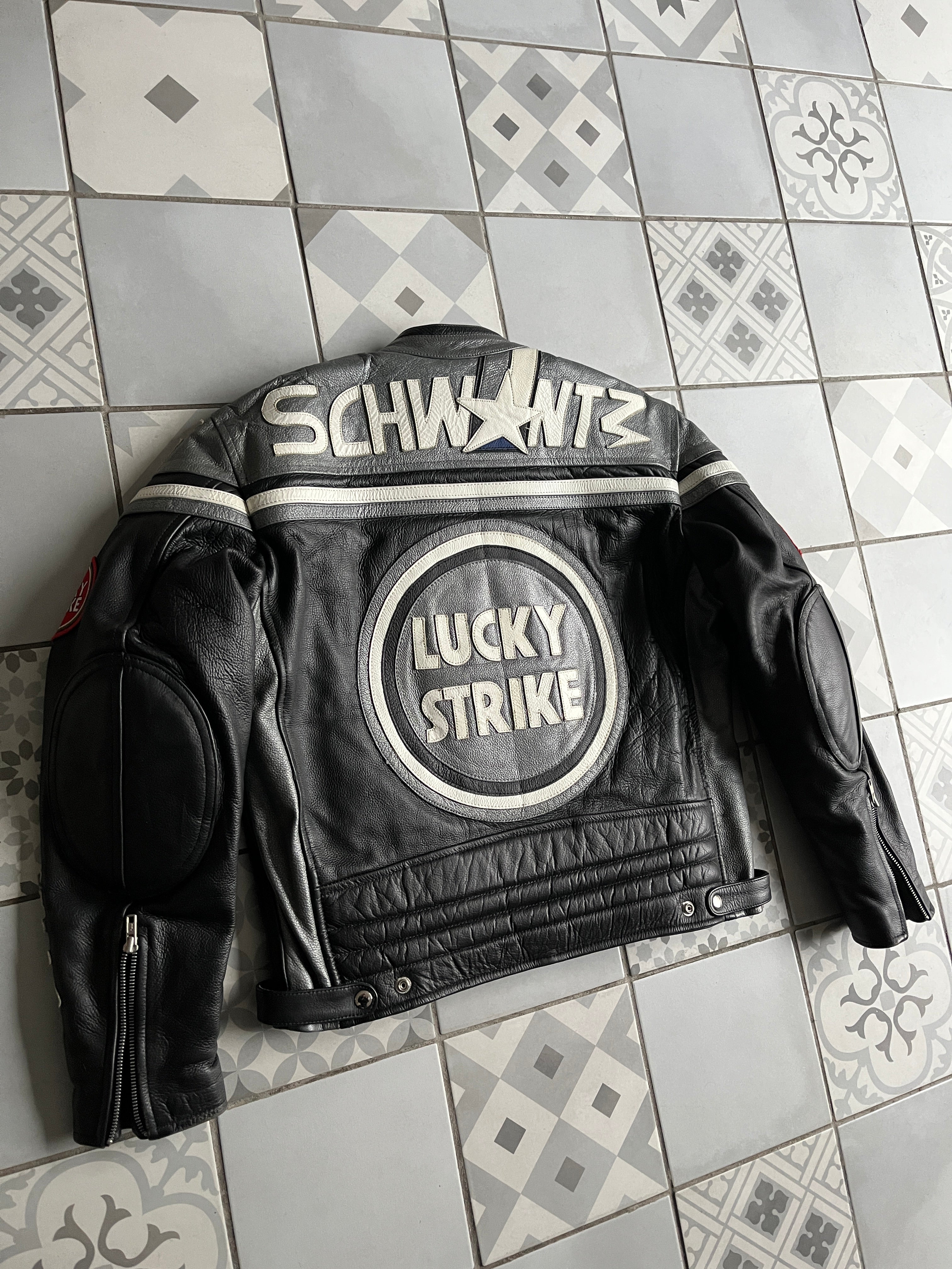 Dos du blouson cuir noir montrant l'immense lettrage SCHWANTZ argenté et le logo Lucky Strike central