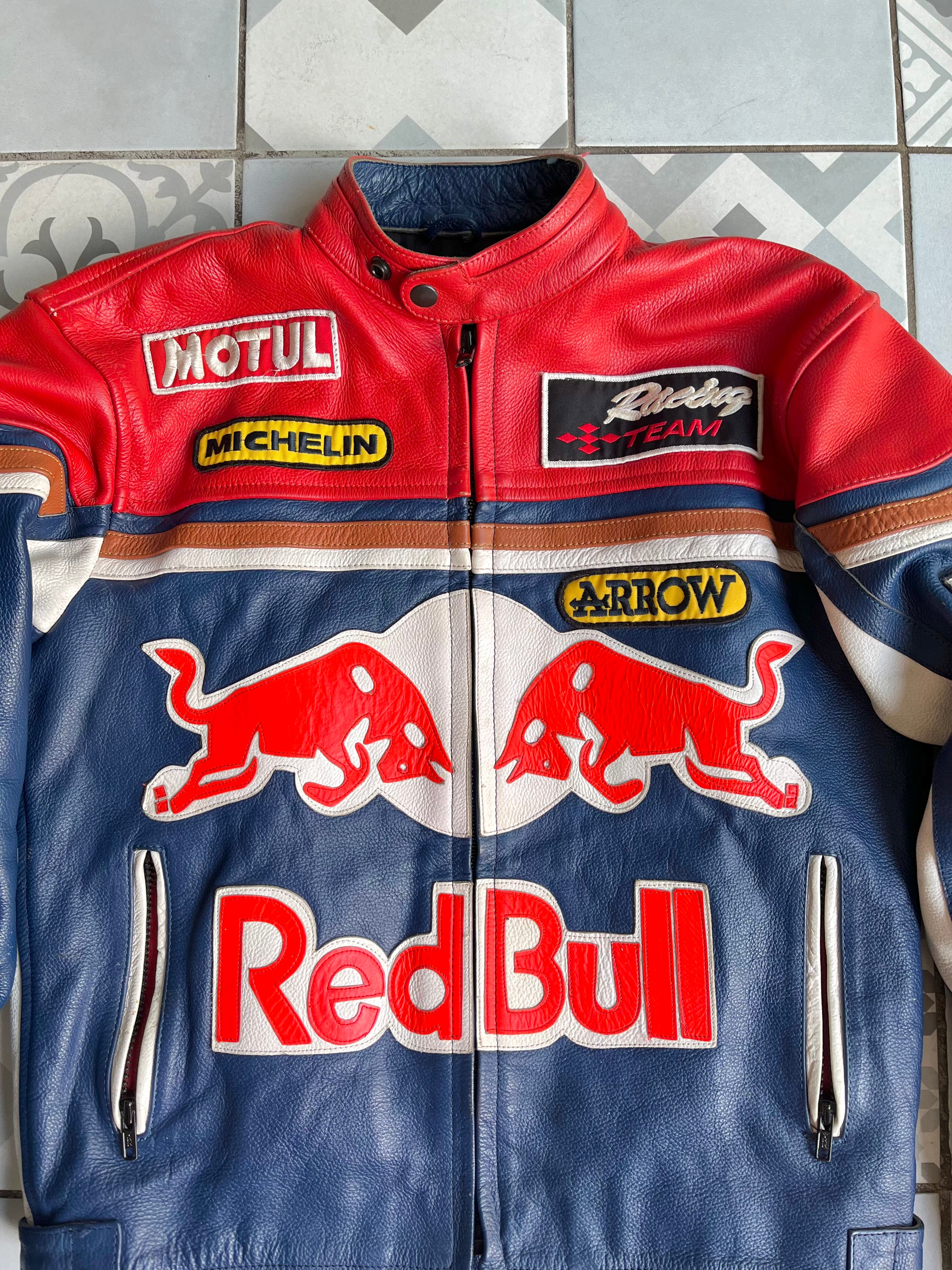Gros plan poitrine veste moto Red Bull : broderies sponsors Motul, Michelin, Arrow, Racing Team et texture cuir grainé.