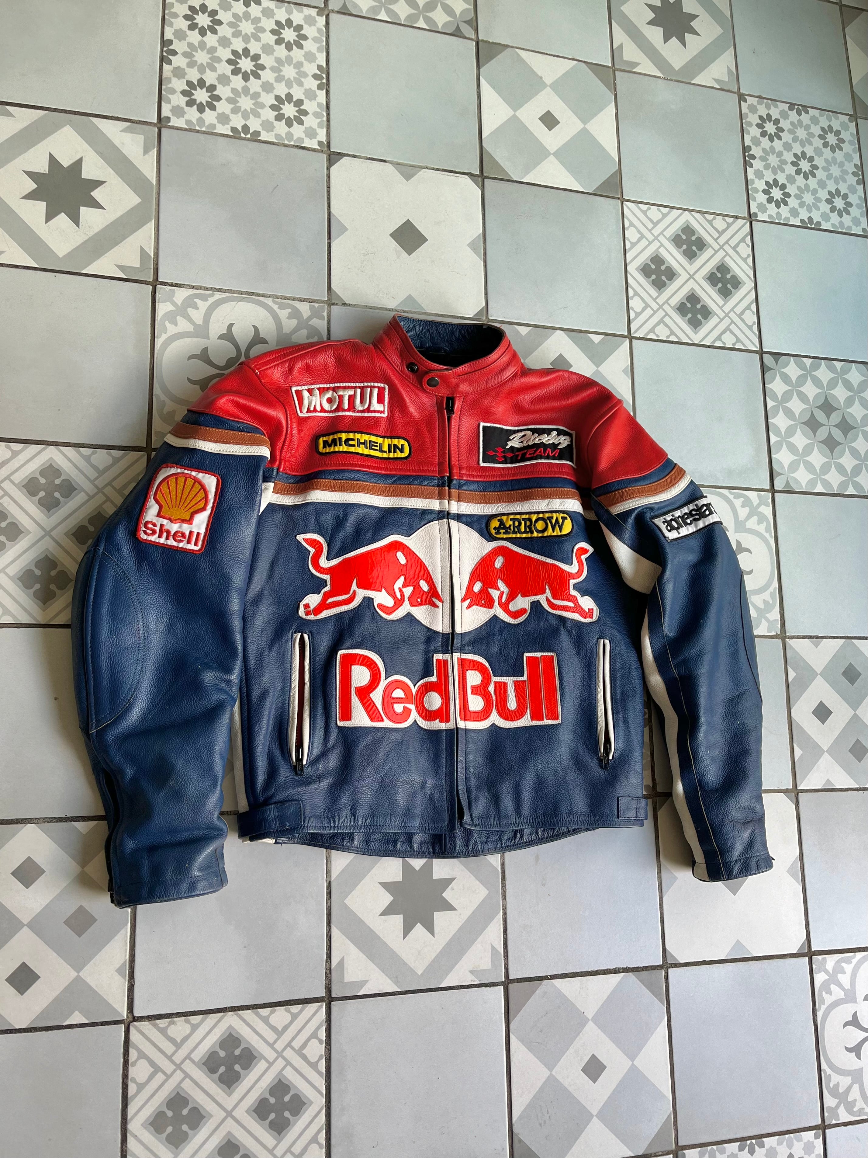 Vue d'ensemble à plat de la veste Red Bull, mettant en valeur la coupe large style motocore et l'imposant logo Red Bull sur l'abdomen.