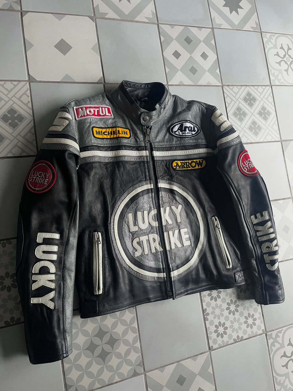 Blouson cuir Lucky Strike noir vu de biais, montrant la coupe sportive, le col motard et les détails argentés.