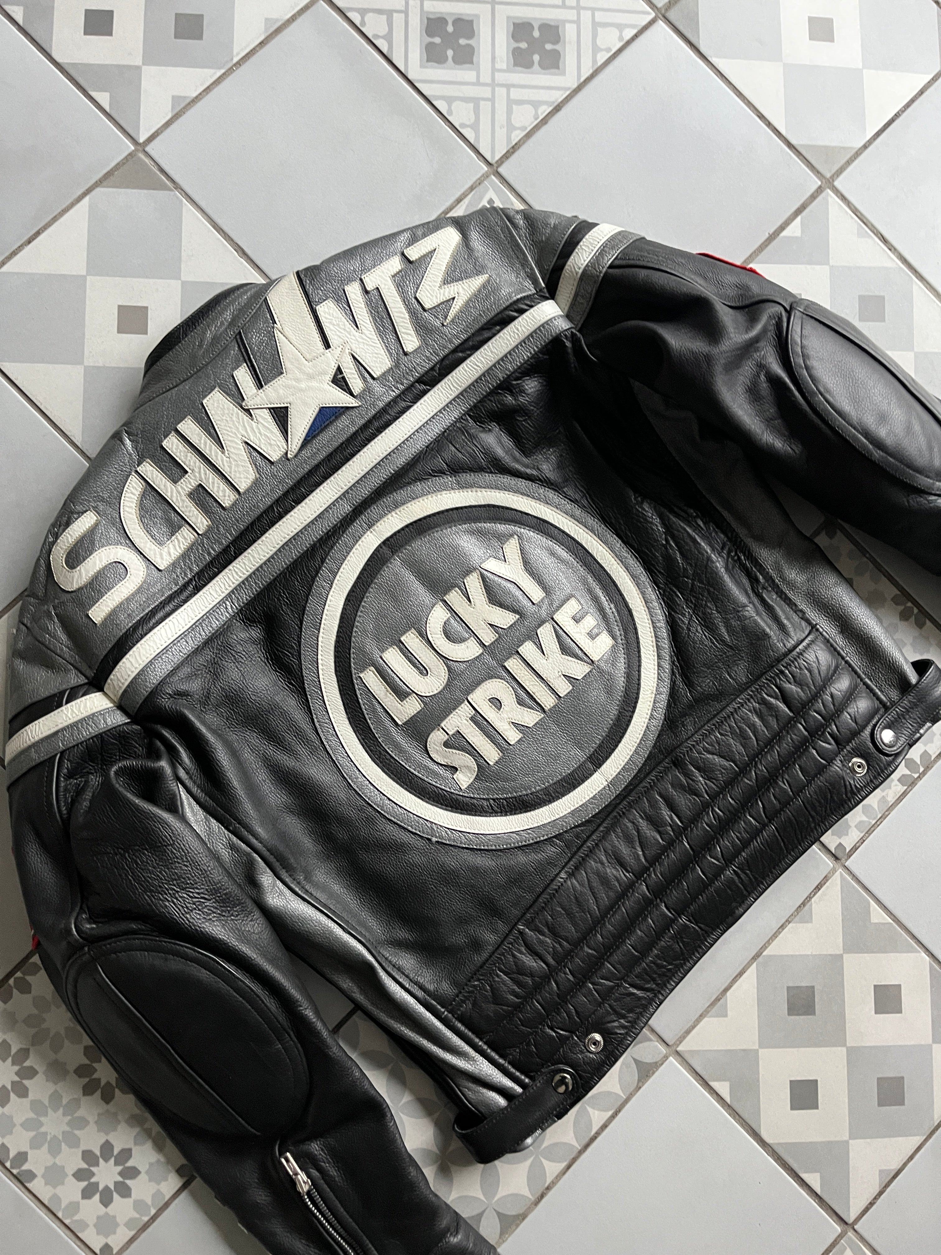 Vue de dos en biais mettant en valeur les renforts d'épaules argentés et la typographie Schwantz brodée