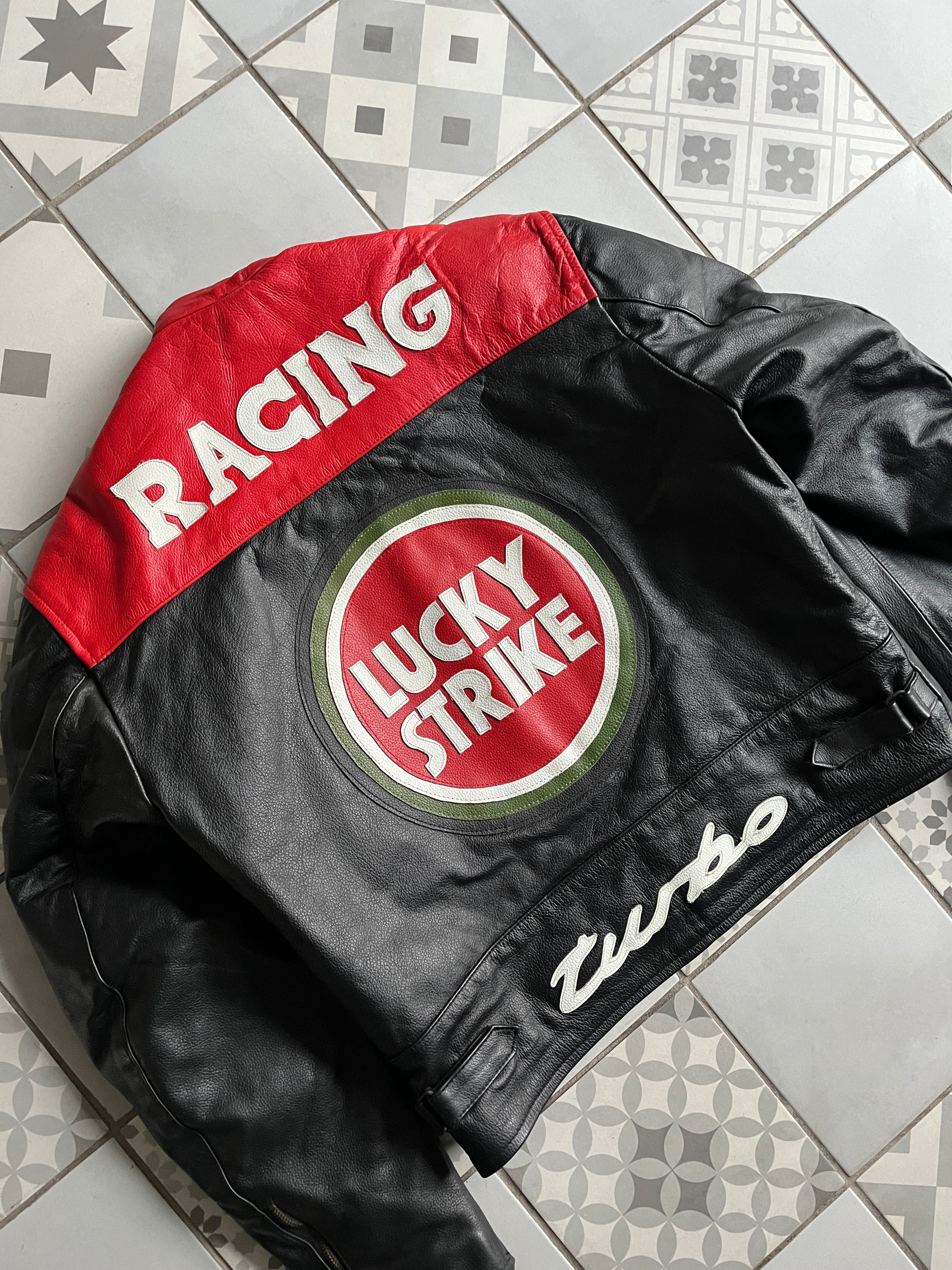 Vue arrière de biais mettant en valeur le logo Lucky Strike, l'empiècement rouge RACING et la coupe motard cintrée